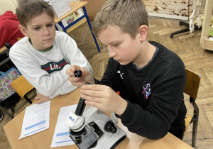 Uczniowie przygotowują mikroskopy do pracy.