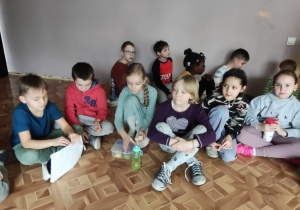 Członkowie Szkolnego Koła UNICEF siedzą i czytają książkę.