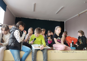Członkowie Szkolnego Koła UNICEF siedzą i czytają książkę.