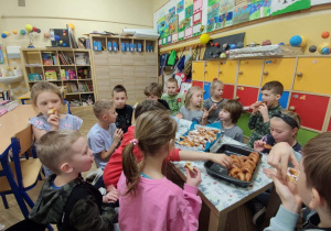 Uczniowie jedzą pączki.