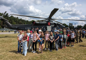 Uczniowie na pamiątkowym zdjęciu w tle śmigłowiec AW-149.