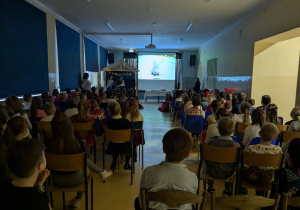 Widok całej sali. uczniowie klas młodszych słuchają o tradycjach świątecznych.