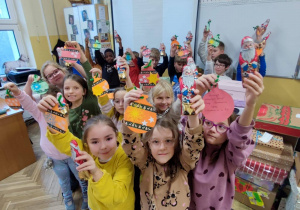 Uczniowie trzymają wykonane przez siebie - kolorowe kartki z życzeniami