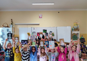 Uczniowie trzymają wykonane przez siebie - kolorowe kartki z życzeniami