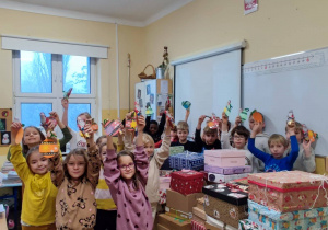 Uczniowie trzymają wykonane przez siebie - kolorowe kartki z życzeniami